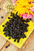Harvest of wild blackberries, fruits and bouquet of pink and yellow flowers