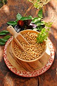 Soybeans (Glycine max) in a wooden pan with Sweet basil (Ocimum basilicum) leaves