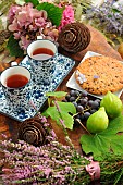 Snack time in the garden: Biscuit, white figs, black grapes, tea and heather bouquet