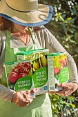 Woman holding boxes of organic fertilizer for different crops.