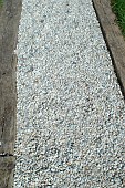 Garden path with white pebbles, borders made of railway sleepers