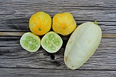 Lemon cucumber (one cut in half) and White Parisian cucumber on a wooden board - Cucumis sativa Lemon and Cucumis sativus L, Hérault, France