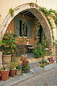 Potted plants under an archway in a village