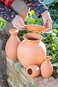 Woman holding various models of oyas, or watering jars, to be buried at the foot of crops.