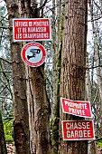 Prohibition signs on tree trunks: Area under video surveillance, No mushrooming, Private property, Game preserve. Le Mans, Sarthe, France