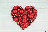 RED HEART OF BAUBLES ON WHITE WOOD