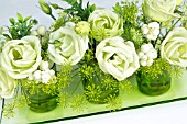 GREEN AND WHITE FLOWER ARRANGEMENT IN GREEN GLASSES