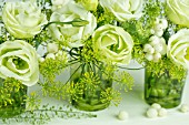 GREEN AND WHITE FLOWER ARRANGEMENT IN GREEN GLASSES