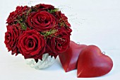 RED ROSES ARRANGEMENT AND A DEEP RED HEART ON WHITE TABLE