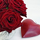 RED ROSES ARRANGEMENT AND A DEEP RED HEART ON WHITE TABLE