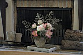 FLOWER ARRANGEMENT WITH ROSES IN FRONT OF FIREPLACE