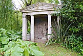 TEMPLE AT MANNINGTON HALL GARDEN, NORFOLK WITH PETASITES, LAURELS AND PHORMIUM