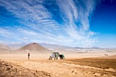 TRACTOR PLOUGHING FURROWS AND PLACING IRRIGATION PIPES IN A DUSTY GROUND IN PALM MAR, TENERIFE, PREPARING TO PLANT A POTATO CROP