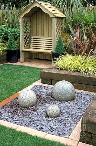 BUBBLE_FOUNTAIN_ON_SLATE_RAISED_RAILWAY_SLEEPER_BEDS_ARBOUR_WITH_SEAT_FOLIAGE_PLANTS_SMALL_COURTYARD