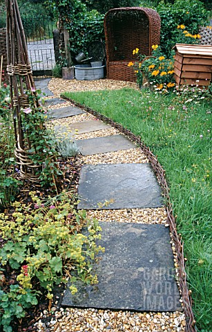 GRAVEL_PATH_WITH_PAVING_INSETS__WITH_OBELISK__WICKER_SEAT_AND_BEE_HIVE__WATTLE_EDGING