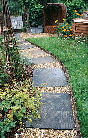 GRAVEL_PATH_WITH_PAVING_INSETS__WITH_OBELISK__WICKER_SEAT_AND_BEE_HIVE__WATTLE_EDGING