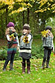 THREE GIRLS COLLECTING FALLEN AUTUMN LEAVES