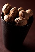 Nutmeg, Mace, Myristica fragrans, Mass of brown coloured spice in cup.
