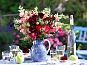 BOUQUET OF ROSES IN A JUG ON A SET TABLE WITH A BOTTLE OF WINE