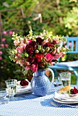 BOUQUET OF ROSES IN A BLUE JUG ON A SET TABLE