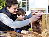 INSECT HOUSE BUILDING PROJECT WITH FATHER AND SON.  ADJUSTING THE BUNDLE FOR FINAL POSITION.  STEP 32