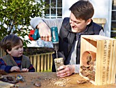 INSECT HOUSE BUILDING PROJECT WITH FATHER AND SON.  DRILLING HOLES INTO LOG.   STEP 22