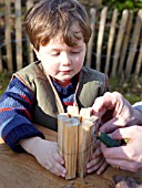 INSECT HOUSE BUILDING PROJECT WITH FATHER AND SON.  TYING STICKS TOGETHER WITH WIRE.  STEP 14