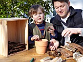 INSECT HOUSE BUILDING PROJECT WITH FATHER AND SON.  PLACING CONES IN POT.  STEP 9