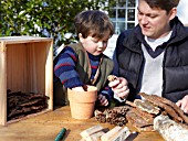 INSECT HOUSE BUILDING PROJECT WITH FATHER AND SON.  PLACING CONES IN POT.  STEP 7