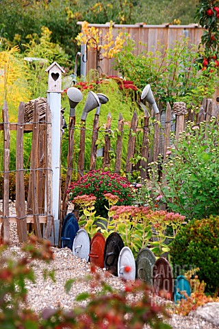 DECORATIVE_EDGING_USING_LIDS_FROM_COOKING_POTS_OLD_WATERING_CAN_ROSES_DECORATING_CHESTNUT_PAILING