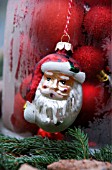 A TABLE IN THE GARDEN DECORATED WITH A BELL JAR FILLED WITH RED CHRISTMAS BALLS  AND SANTA