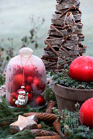 A_TABLE_IN_THE_GARDEN_DECORATED_WITH_A_BELL_JAR_FILLED_WITH_RED_CHRISTMAS_BALLS