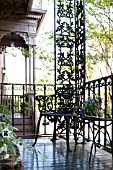 BLACK CAST IRON CHAIR ON DECORATIVE IRON BALCONY IN URBAN GARDEN