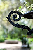 ORNATE HANDLE OF IRON URN IN FORMAL GARDEN