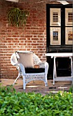 CHLOROPHYTUM COMOSUM, SPIDER PLANT, IN WALL PLANTER ON PATIO WITH WICKER CHAIR