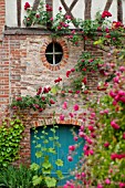 RED CLIMBING ROSES OVER BRICK AND HALF TIMBERED MEDIEVAL BUILDING