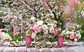 MALUS X EVERESTE WITH OUTDOOR TABLE SET UNDER APPLE BLOSSOMS AND DECORATED WITH FLORAL ARRANGEMENTS OF RANUNCULUS AND ROSES