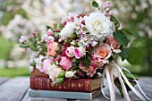 MALUS X EVERESTE  ROSA  RANUNCULUS ASIATICUS IN BOUQUET ON VINTAGE BOOKS