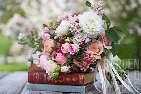 MALUS_X_EVERESTE__ROSA__RANUNCULUS_ASIATICUS_IN_BOUQUET_ON_VINTAGE_BOOKS