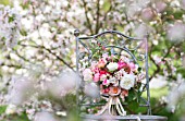 MALUS X EVERESTE  ROSA  RANUNCULUS ASIATICUS IN BOUQUET ON VINTAGE CHAIR