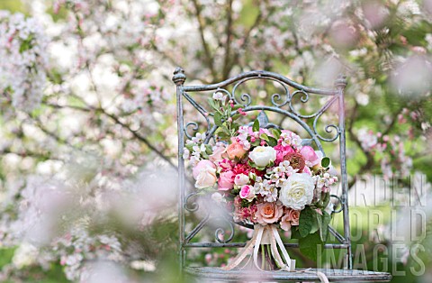 MALUS_X_EVERESTE__ROSA__RANUNCULUS_ASIATICUS_IN_BOUQUET_ON_VINTAGE_CHAIR