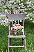 MALUS X EVERESTE  ROSA  RANUNCULUS ASIATICUS IN BOUQUET ON VINTAGE CHAIR