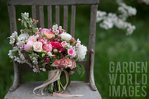 MALUS_X_EVERESTE__ROSA__RANUNCULUS_ASIATICUS_IN_BOUQUET_ON_VINTAGE_CHAIR