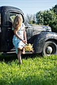 GIRL WITH BOUQUET OF DAVID AUSTIN ENGLISH ROSES GRAHAM THOMAS AND PORT SUNLIGHT WITH HERBS AND SEED HEADS ON OLD TRUCK