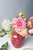 FLORAL DESIGNER ARRANGING BOUQUET WITH ZINNIA, DAHLIA, ROSE, SNAPDRAGON AND OTHER SUMMER FLOWERS