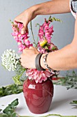 FLORAL DESIGNER ARRANGING BOUQUET WITH ZINNIA, DAHLIA, ROSE, SNAPDRAGON AND OTHER SUMMER FLOWERS