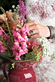 FLORAL DESIGNER ARRANGING BOUQUET WITH ZINNIA, DAHLIA, ROSE, SNAPDRAGON AND OTHER SUMMER FLOWERS