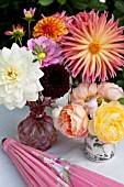 MIXED DAHLIAS AND ROSES IN VASES ON OUTDOOR GARDEN TABLE