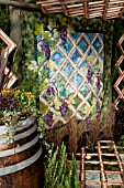 OUTDOOR PATIO GARDEN WITH TRELLIS PERGOLA, QUILT WALL HANGING, TILE AND MOSS FLOOR.