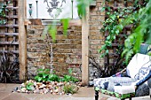 THE DRAWING ROOM GARDEN  URBAN LONDON GARDEN  WATER FEATURE AND CHAIR WITH FILIGREE PATTERN WALL PLAQUE  DESIGNED BY: EARTH DESIGNS.